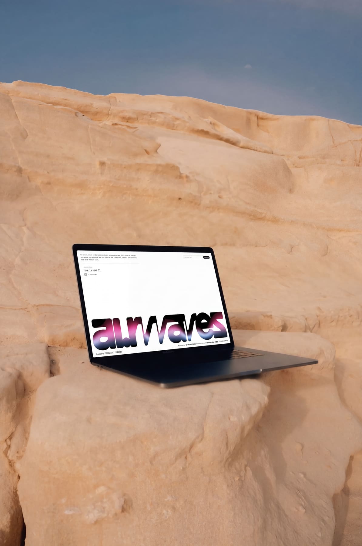 Laptop showing the ai.rwaves site, resting on a desert rock